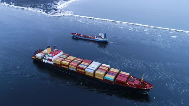 Aerial Shot of the Cargo Ship Moving Through the Sea. In the Background Winter Landscape. Shot on 4K UHD Camera.