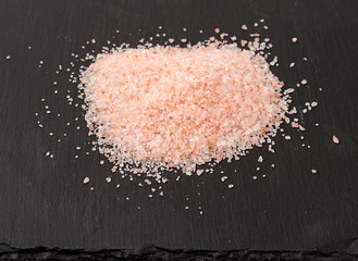 Himalayan pink salt on black stone background
