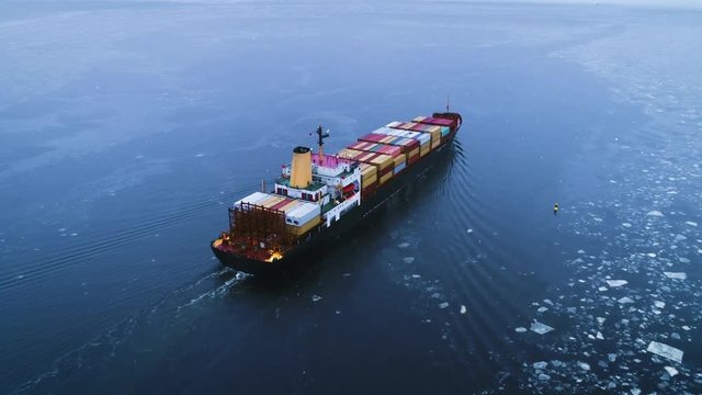Aerial Shot of the Cargo Ship Moving Through the Sea. In the Background Winter Landscape. Shot on 4K UHD Camera.