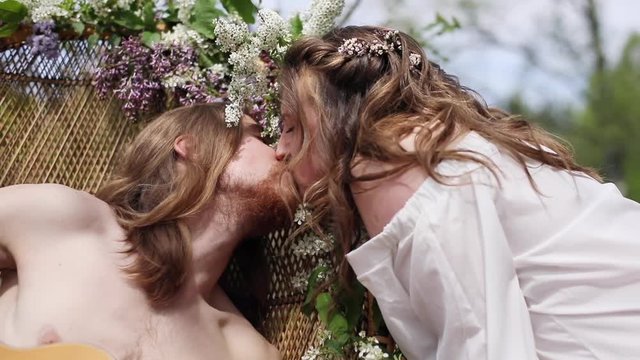Young man woman kissing outdoors nature green defocused background romantic date close up manual. Sweet moments of love beautiful sexy couple with long hair wild flowers acoustic guitar hot summer day