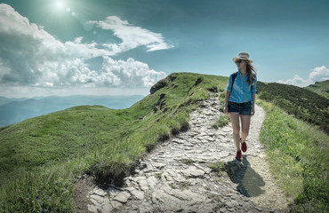 Fototapeta premium Woman hiking in mountains at sunny day time.