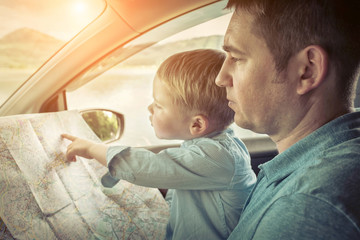 Father and son looking on map in car