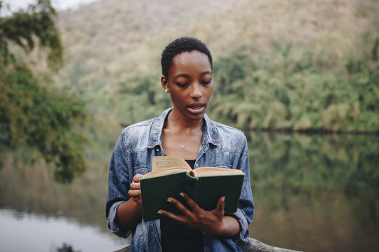African American woman alone in nature reading a book leisure concept