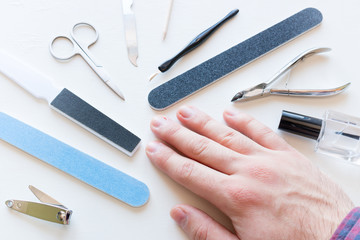 man with not well-groomed nails and tools for manicure