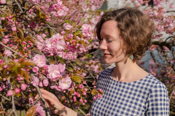 Fototapeta premium Outdoor portrait of a beautiful woman near sakura tree with flowers. 