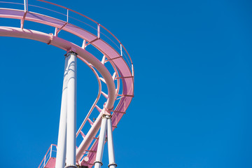 Pink pastel looping roller coaster on blue sky sunny day background.