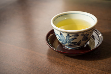 A ceramic cup of traditional Japanese tea on wooden table