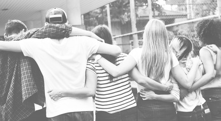 Smiling happy young adult friends arms around shoulder outdoors friendship and connection concept
