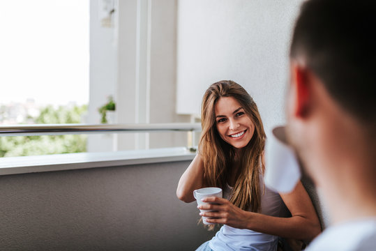 Young Couple Drinking Morning Coffee On The Balcony.