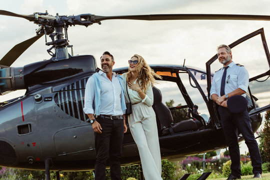 Couple standing by a helicopter with pilot