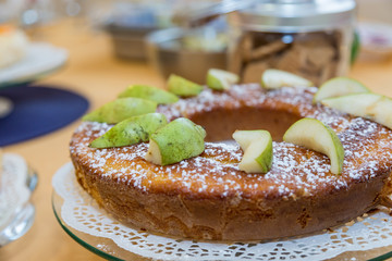 Sweet breakfast. Close-up of circular sponge cake with pear slices and icing sugar