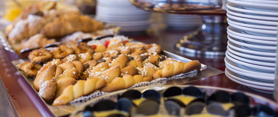 Close-up of a tray with assorted cookies. Sweet buffet breakfast and stack of plates on the table