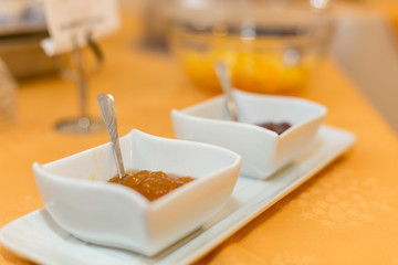 Close-up of white bowls with jam on a yellow tablecloth