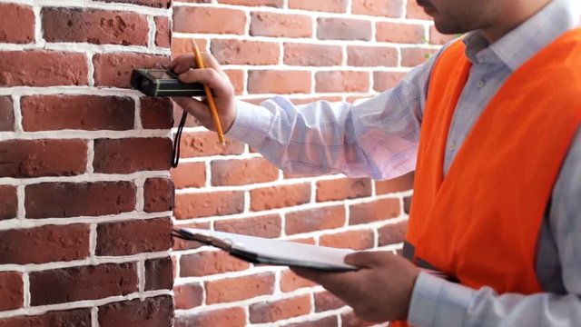 A young construction engineer makes room measurements with a laser roulette