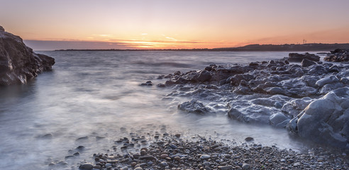 Sunset off the South Wales coast. Ogmore-by-Sea is a popular destination to swim and surf. A long shutter speed has been used to create a milky sea effect
