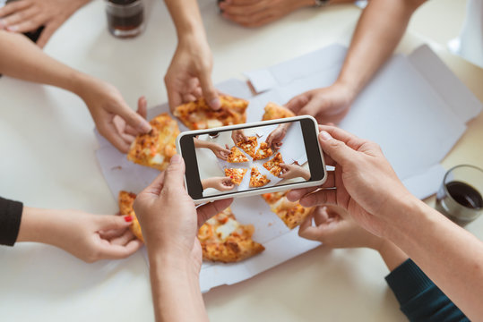 Photographing food. Hands taking picture of delicious pizza with smartphone.