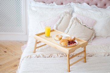 Fototapeta na wymiar Breakfast in bed on a tray, freshly squeezed juice and croissants