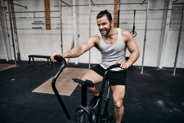 Plakat Smiling man riding a stationary bike at the gym