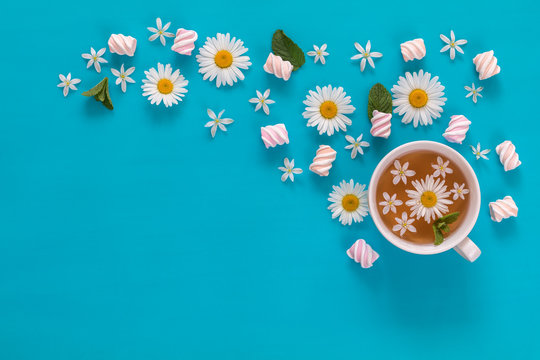 Cup of tea with marshmallows and flowers blossom  bouquets on blue surface