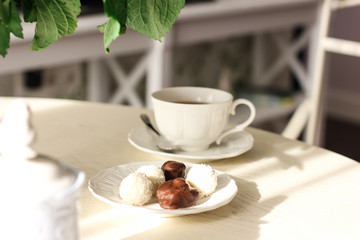 Sunlit dining table with flowers, tea and sweets