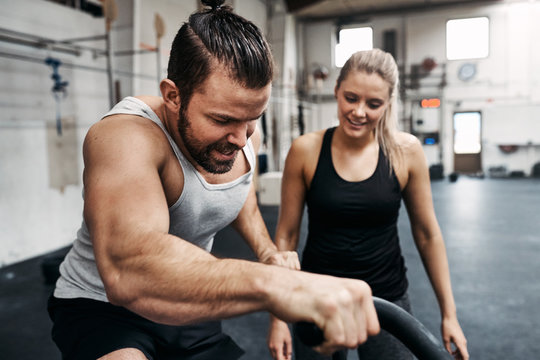 Smiling young woman watching her gym partner ride a bike