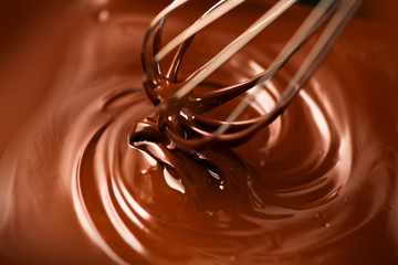 Chocolate. Mixing melted dark chocolate with a whisk. Closeup of liquid hot chocolate swirl. Confectionery