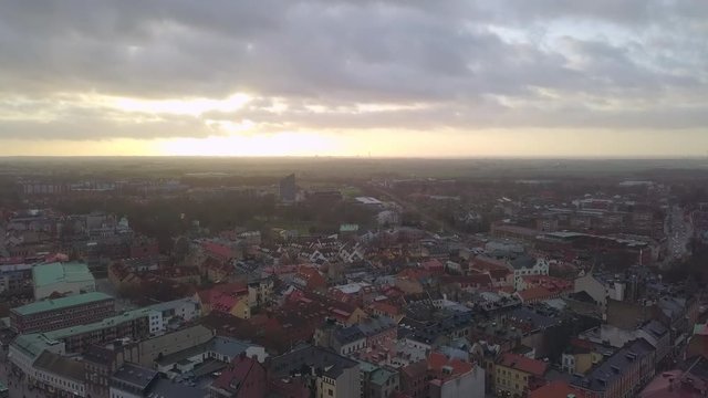 Aerial view of Lund city and Cathedral church building at sunset. Drone shot flying down over cityscape skyline and church tower spire