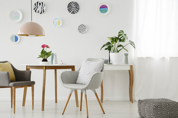 Retro armchairs, table, chandelier, ceramic wall decoration and pouf in a bright apartment interior