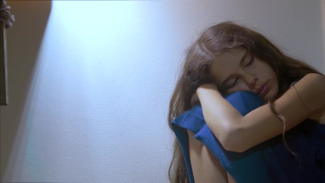 sad girl upset embraces her feet. is depressed and suicidal little lamentable girl schoolgirl sadness misses the night in bed concept childhood family. lifestyle the problem of education in the family