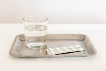 Tabletten auf Tablet mit Glas Wasser, Krankheit, Krankenhaus, Medikamente