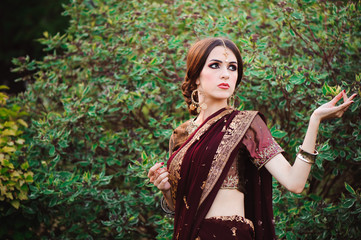 Naklejka premium Beautiful young caucasian woman in traditional indian clothing sari with bridal makeup and jewelry and henna tattoo on hands