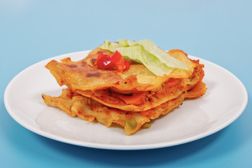 Lasagna with vegetables on a blue