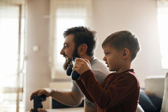 Little boy playing computer game with his father at home