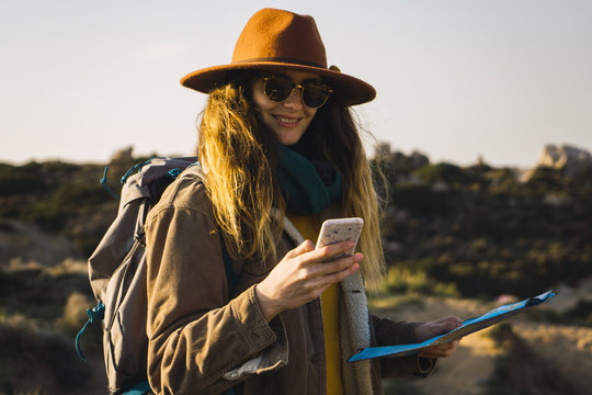 Italy, Sardinia, smiling woman on a hiking trip holding cell phone and map - Powered by Adobe