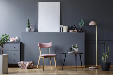 Pink wooden chair at black table in grey living room interior with mockup of empty poster