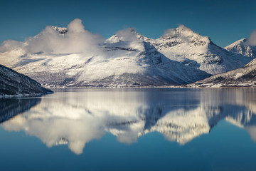 Three mountain peaks covered with snow by the northern Norway fjord