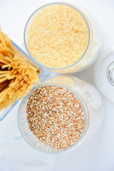 Spaghetti in the form of a bouquet in a transparent vase, next to transparent containers with buckwheat and rice