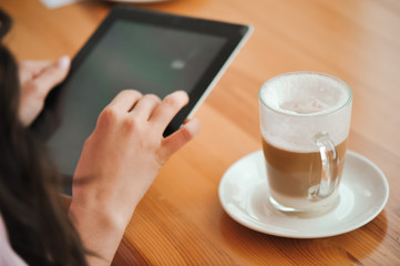 girl in cafe uses small mobile computer