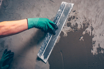 A wide spatula in the hands of the worker, facing works