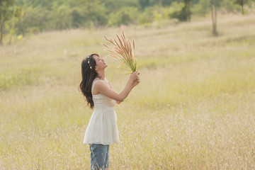 Beautiful woman enjoying meadow field, nice female lying down in meadow of flowers, pretty girl relaxing outdoor, having fun, holding plant, happy young lady and spring green nature, harmony concept