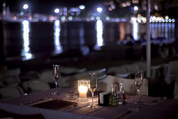 Table with candles on the beach of the evening cafe