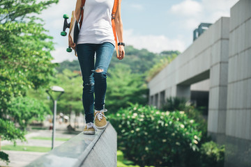 Young woman walking on the edge of a urban building wall at city