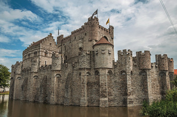 Fototapeta na wymiar Lake and stone wall in front of Gravensteen Castle on cloudy day in Ghent. In addition to intense cultural life, the city is full of Gothic buildings and Flemish style architecture. Northern Belgium.
