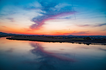 倉敷川の夕暮れ時に川面に空と雲がが映る、枯た木と魚の波紋がアクセント