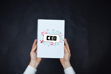 In the hands of a businessman a notebook with the inscription:CEO