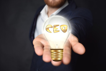 A businessman is holding a light bulb with the inscription:CEO