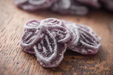 closeup of traditional purple candies in shaped flower on wooden background