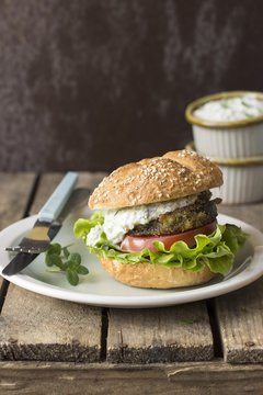 A burger with fried aubergine, tzatziki, tomato and lettuce