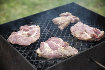 Raw steaks grilling on BBQ