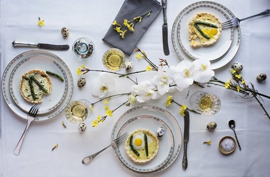 Asparagus quiche with fried quail egg on a dining table set for Easter